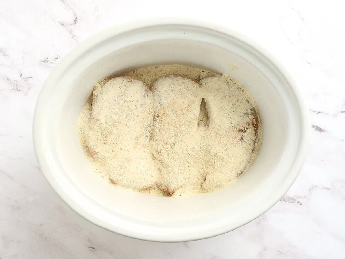 Poitrines de poulet dans une mijoteuse avec assaisonnements.