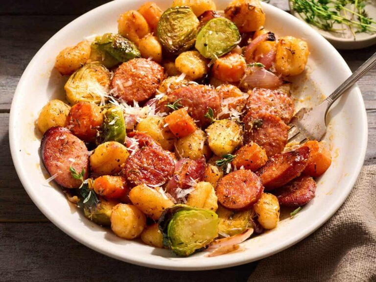 Side view of gnocchi with sausage and fall vegetables in a bowl.