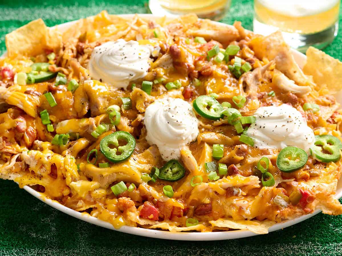 Vue latérale d'un plateau de nachos garni de chili végétarien, de crème sure et de jalapenos.